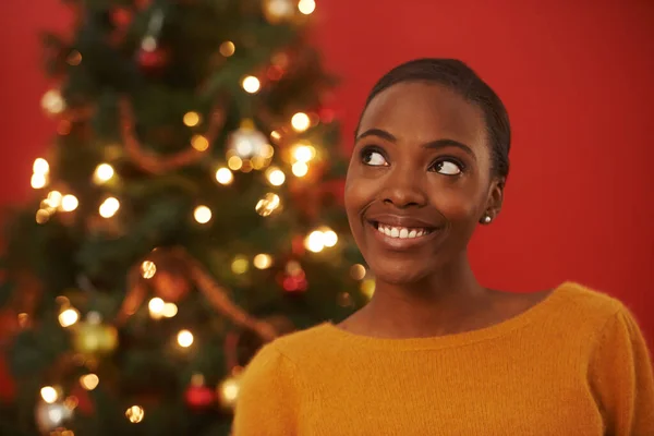 Feestelijke gedachten. Opname van een aantrekkelijke jonge vrouw die voor een kerstboom staat. — Stockfoto