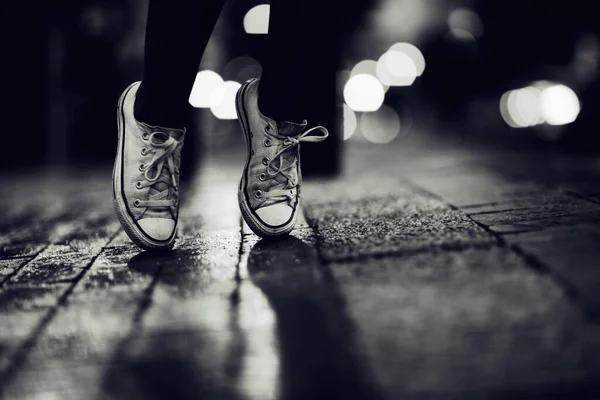 Місто вночі. Обрізане зображення людини, яка носить кросівки, стоячи на пальцях на вулиці . — стокове фото