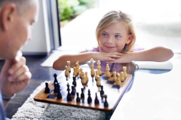 Enseñándole la habilidad de la estrategia. Un padre jugando al ajedrez con su hija pequeña. — Foto de Stock