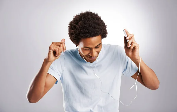 Musik är en säker typ av hög. Studio bild av en ung man lyssnar på musik på sin mobiltelefon. — Stockfoto