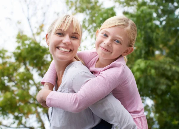 Eingehüllt in die Liebe meiner Töchter. Eine glückliche junge Mutter schenkt ihrer Tochter eine Huckepackfahrt im Park. — Stockfoto