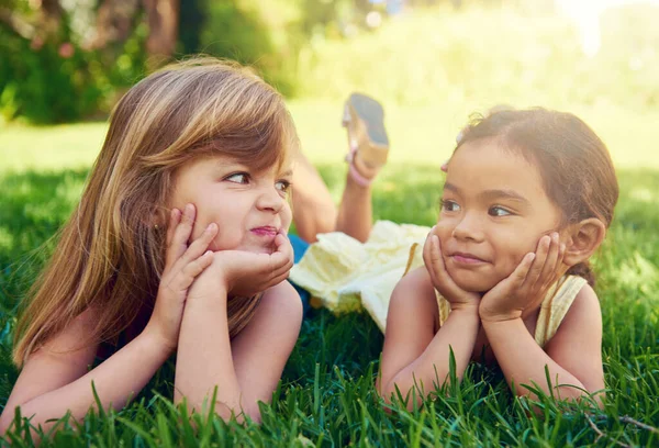 어린 시절의 우정. 사랑 스러운 두 어린 소녀 가 풀밭에서 서로 옆에 누워 있는 모습을 찍은 사진. — 스톡 사진