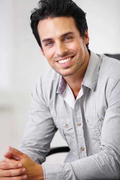 A confident smile makes everything worthwhile. Shot of a handsome young sitting in a chair. — Stock Photo, Image