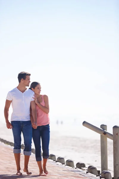 Amore e una splendida vista. Colpo pieno di una giovane coppia attraente che cammina accanto al mare. — Foto Stock