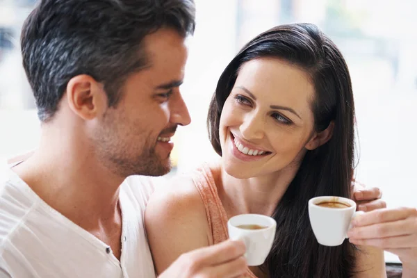 Loving expressions over their espresso. Shot of a young couple grabbing a cup of coffee together. Stock Picture