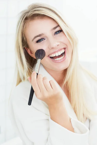 Blushing cheeks. A gorgeous young woman in her bathrobe applying blusher. — Stock Photo, Image