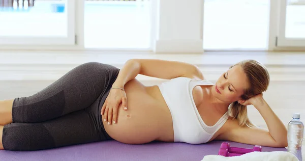 Mama kan niet wachten om je te ontmoeten. Gehakt schot van een aantrekkelijke jonge zwangere vrouw liggend op haar zij op een yoga mat. — Stockfoto