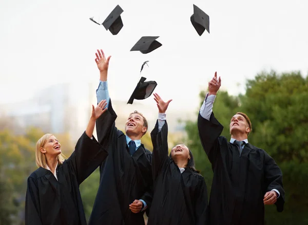 E 'qui per il resto della nostra vita. Un gruppo di studenti getta i berretti in aria dopo la laurea. — Foto Stock