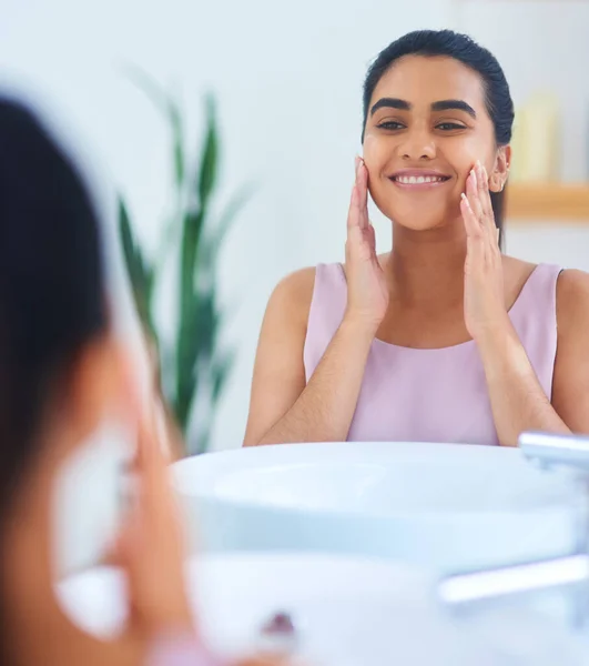 Not a single blemish in sight. Shot of a young woman applying moisturiser to her face in a bathroom at home. — Stock Photo, Image