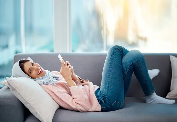 Verbunden mit dem Komfort meiner Couch. Porträt einer attraktiven jungen Frau, die einen Text schreibt, während sie zu Hause auf ihrem Sofa chillt. — Stockfoto