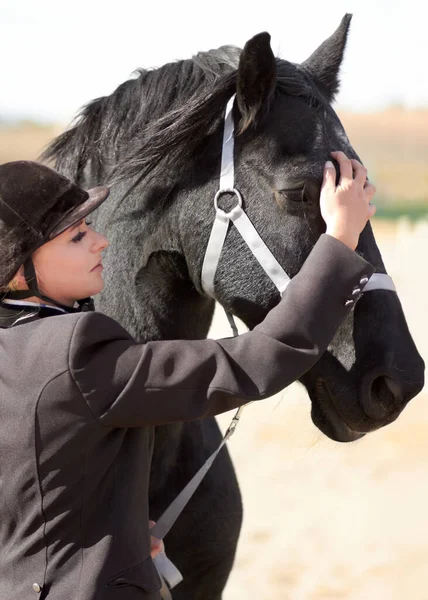 Getting ready for a long ride. Shot of a young female rider stroking her horses face. — Stock Photo, Image