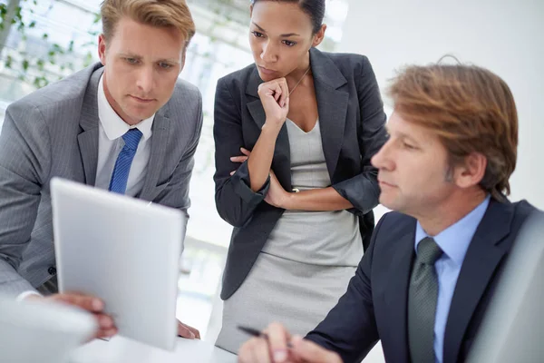 Tienen que tomar algunas decisiones importantes. Un joven empresario mostrando a sus colegas algo en una tableta digital. —  Fotos de Stock