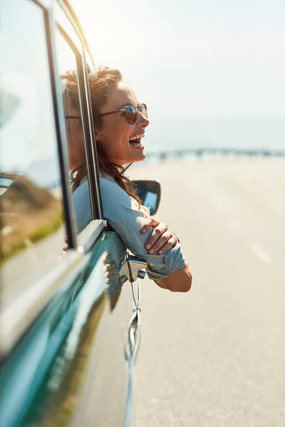 Känn dig fri på den öppna vägen. Beskuren bild av en attraktiv kvinna som hänger ut genom ett bilfönster medan du njuter av en roadtrip. — Stockfoto