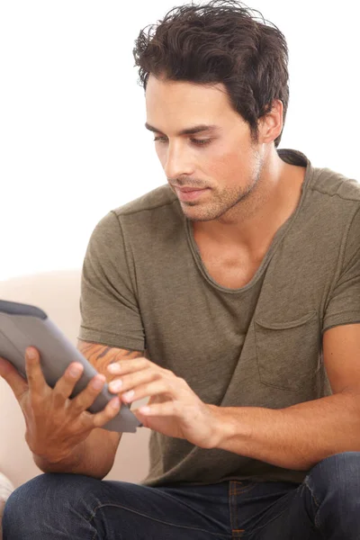 Zafascynowany nową tabliczką. Przystojny młody mężczyzna korzystający z tabletu cyfrowego siedząc na kanapie w domu. — Zdjęcie stockowe