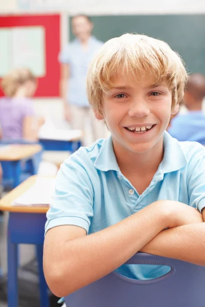 He loves class. Portrait of a cute blonde schoolboy in sitting at a desk in class. — Stock Photo, Image
