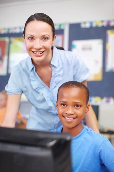 Il pourrait avoir un brillant avenir en informatique. Portrait d'une belle jeune femme aidant un jeune garçon ethnique en classe d'informatique. — Photo