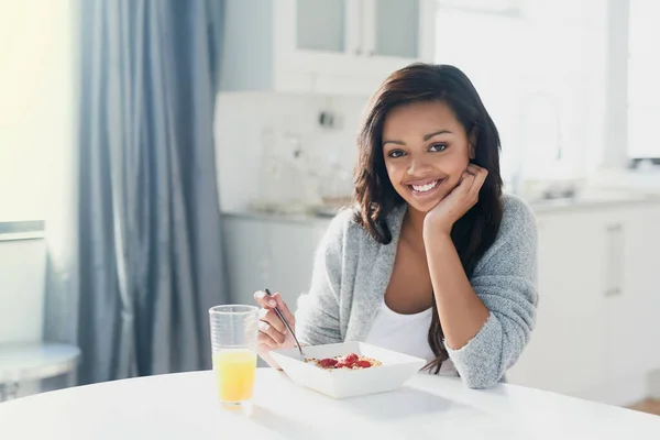 Glowing with health and happiness. Portrait of a happy young woman enjoying a healthy breakfast at home. — Stock Photo, Image