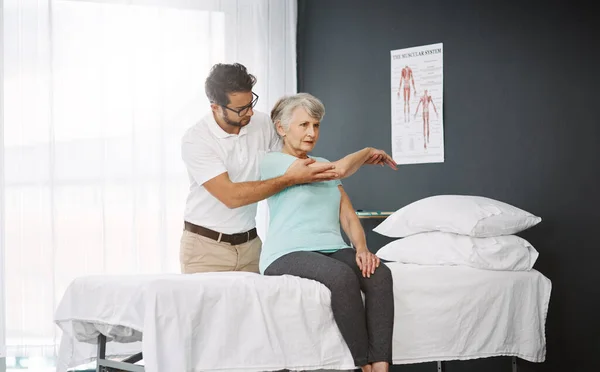 Wat een pijn. Gesneden foto van een jonge mannelijke fysiotherapeut die werkt met een oudere vrouwelijke patiënt. — Stockfoto