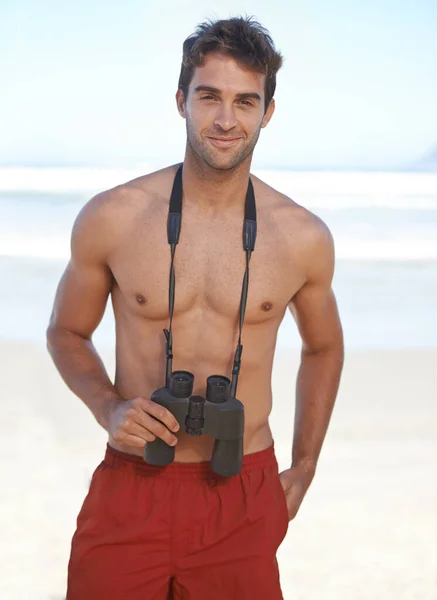 Está buscando peligro en el agua. Un joven salvavidas guapo en la playa. —  Fotos de Stock