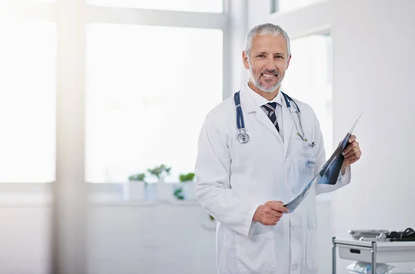 Engagé à l'excellence dans les soins de santé. Portrait d'un médecin mature tenant une radiographie dans un hôpital. — Photo