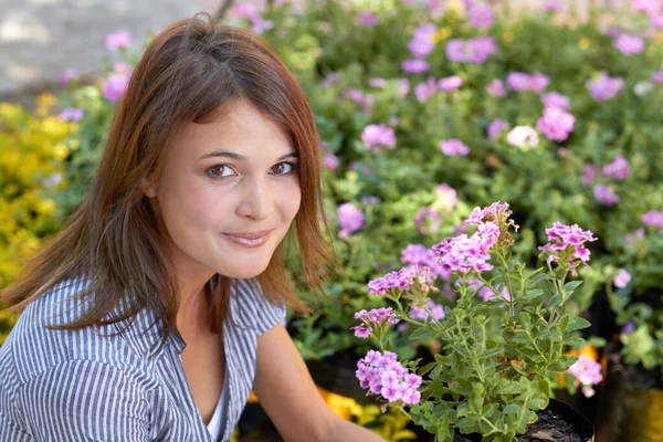 I grew these myself. A pretty mature woman sitting among her gardens many blooms. — Stock Photo, Image