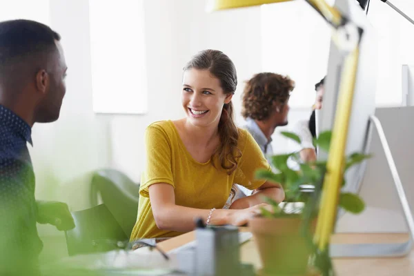 Condividere una risata di lavoro. Girato di un team di designer che parlano mentre lavorano sui loro computer. — Foto Stock