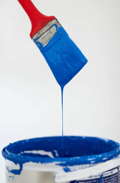 Pincel pingando tinta azul. Closeup de um pincel pingando tinta azul em um balde. — Fotografia de Stock
