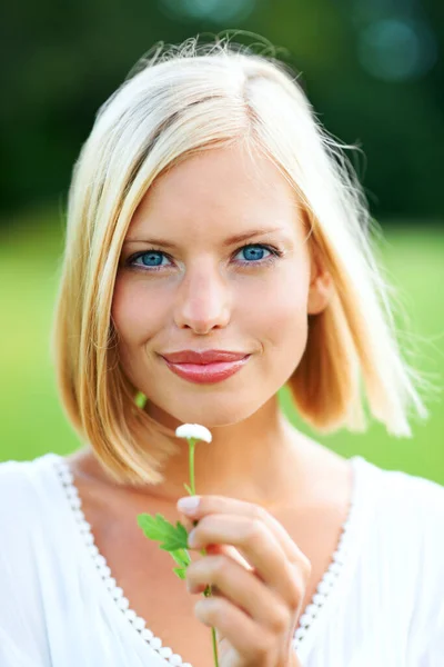 彼女は天然のスタントマンです。小さな花を屋外で保持する豪華な若い女性. — ストック写真
