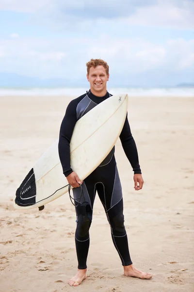 Auf zum Surfen. Ein junger Mann mit seinem Surfbrett am Strand. — Stockfoto
