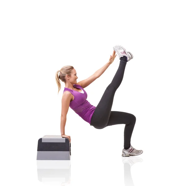 Equilibrio e tono. Una giovane donna sorridente che fa aerobica su un gradino aerobico isolato su uno sfondo bianco. — Foto Stock