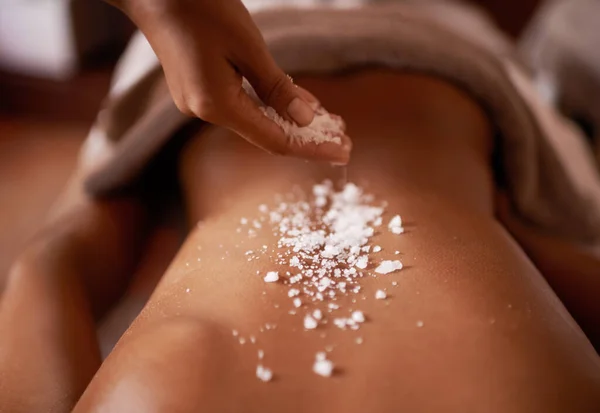 O ingrediente perfeito para ajudar a destress..... Tiro de uma jovem mulher desfrutando de um tratamento de esfoliação de sal em um spa. — Fotografia de Stock