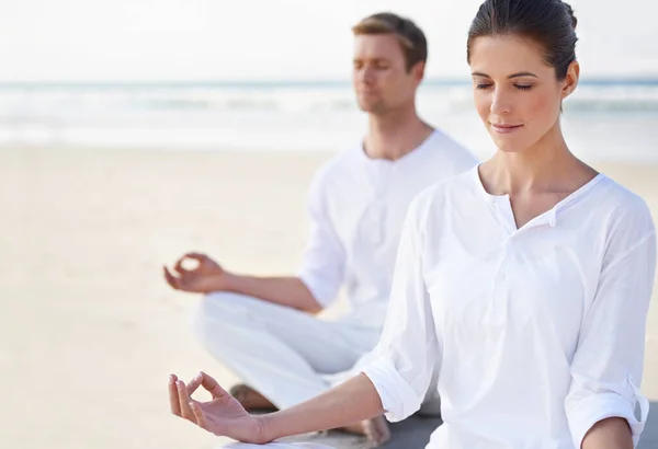 Yoga am Meer. Ein junges Paar praktiziert Yoga am Strand. — Stockfoto