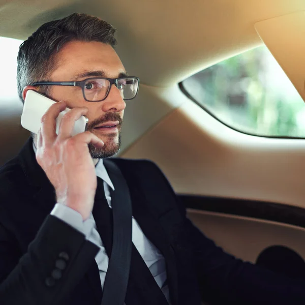 Vou buscar-te pelo caminho. Tiro cortado de um homem de negócios usando seu celular enquanto sentado no banco de trás de um carro. — Fotografia de Stock