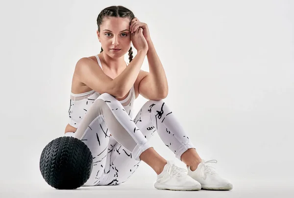 Te prometo que soy mucho más agradable que mi cara de gimnasio en reposo. Retrato de estudio de una joven deportista posando con una pelota de ejercicio sobre un fondo blanco. — Foto de Stock