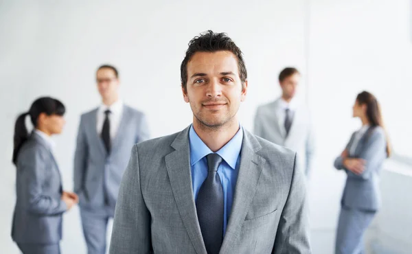 Je součástí dynamického obchodního týmu. Portrét pohledného mladého podnikatele se svými kolegy stojící v pozadí. — Stock fotografie