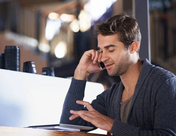 Kahve için bir arkadaşımı arıyorum. Bir kafede oturan genç bir adam cep telefonuyla konuşuyor ve dijital tablet üzerinde çalışıyor.. — Stok fotoğraf