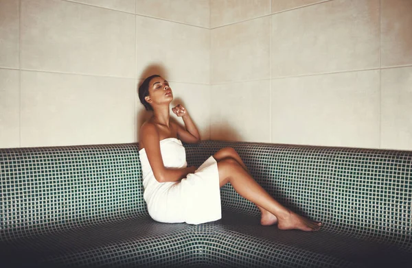 Disfrutando de las cosas simples de la vida. Foto completa de una mujer joven relajándose en la sauna en un spa. — Foto de Stock