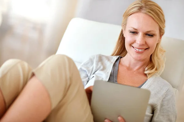 Evde kullanışlı bir teknoloji var. Oturma odasında dijital tablet kullanan bir kadının fotoğrafı.. — Stok fotoğraf