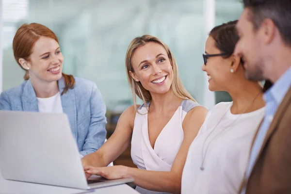 Hacer el trabajo juntos. Un grupo diverso de empresarios que utilizan un ordenador portátil en una reunión. — Foto de Stock