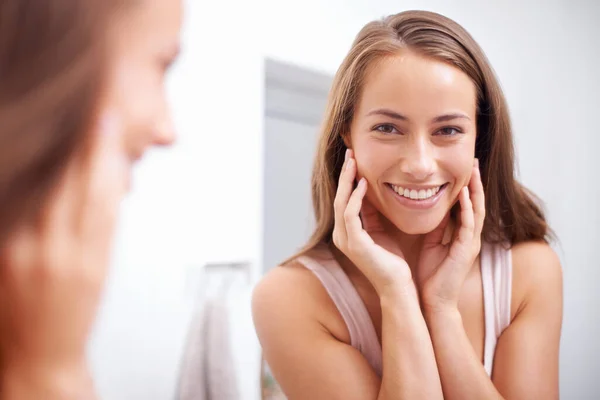 Shes the fairest of them all. A young woma touching her face happily as she looks in the mirror. — Stock Photo, Image
