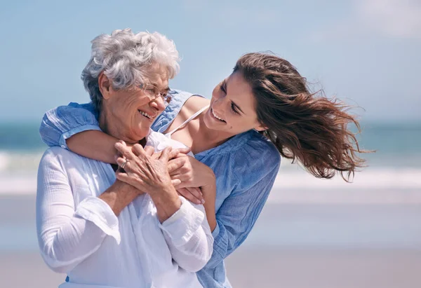 Tomarse el tiempo para mostrar algo de ternura. Foto de una hermosa joven y su madre mayor en la playa. —  Fotos de Stock