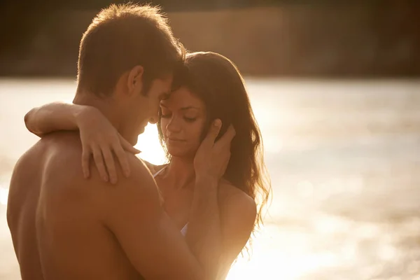 Ένα σπίρτο φτιαγμένο... στην παραλία. Ένα νεαρό ζευγάρι που μοιράζεται μια ρομαντική στιγμή σε μια παραλία. — Φωτογραφία Αρχείου