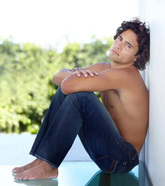 Njuter av lugnet i ensamheten. Porträtt av en stilig ung man som sitter mot en vägg hemma. — Stockfoto