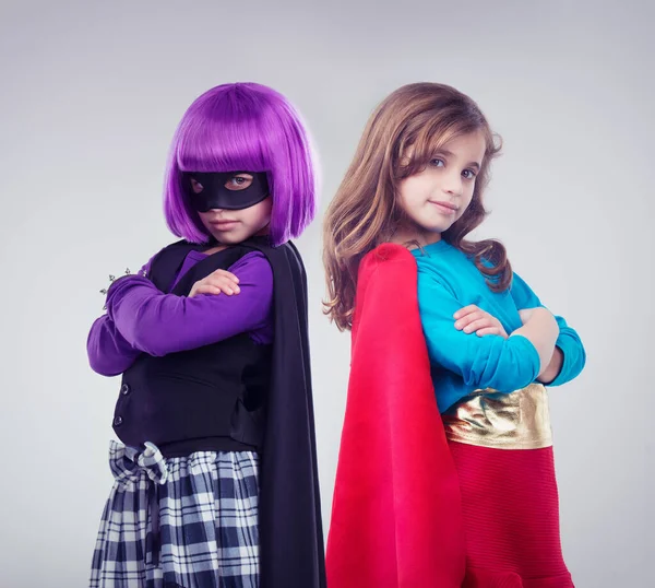 Tidak semua gadis ingin menjadi putri kecil. Sebuah gambar studio dari dua gadis kecil berpakaian seperti pahlawan super dan penjahat. — Stok Foto