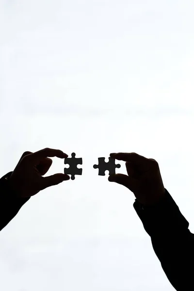 Vedendo il quadro generale. Colpo ritagliato di due persone che tengono insieme pezzi di puzzle su uno sfondo bianco. — Foto Stock