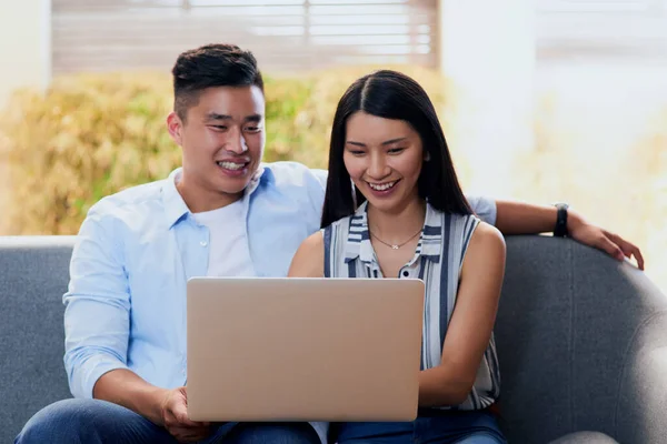 Descontrair na nova era. Tiro de um jovem casal feliz usando um laptop juntos no sofá em casa. — Fotografia de Stock