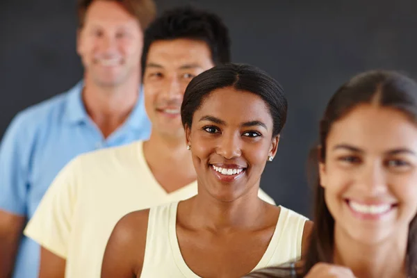 Står ut från mängden. Porträtt av en attraktiv afrikansk kvinna som står i kö med sina kamrater ur fokus. — Stockfoto