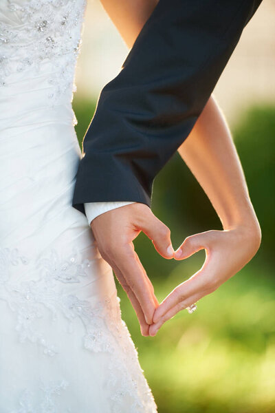 The shape of love. Cropped image of a newlywed couple making a heart with their hands.