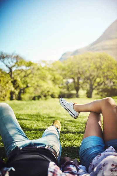 La vita è piena di bei momenti. Colpo ritagliato di una giovane coppia sdraiata sull'erba al parco. — Foto Stock