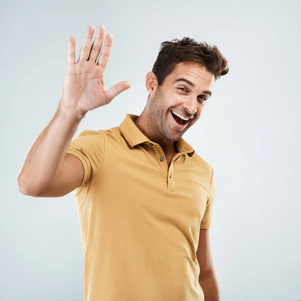Gaan we een high five doen. Portret van een vrolijke jongeman die fel glimlacht met zijn ene hand in de lucht terwijl hij tegen een grijze achtergrond staat. — Stockfoto